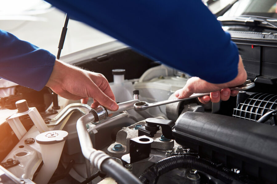 Hands of car mechanic with wrench in garage.